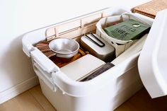 a white container filled with lots of items on top of a wooden floor