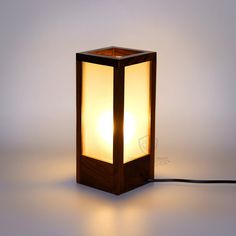 a wooden table lamp with a white light on it