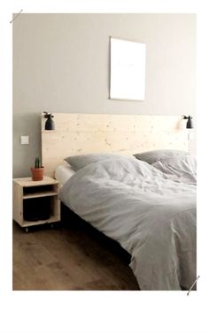 a white bed sitting next to a wooden nightstand on top of a hard wood floor