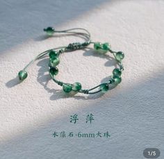 a bracelet with green glass beads on white paper and chinese characters written in the background