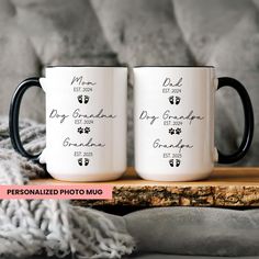 two black and white coffee mugs sitting on top of a wooden table