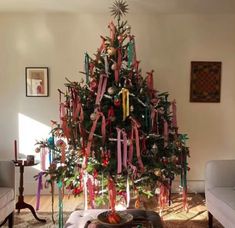 a decorated christmas tree in a living room with ribbons on it's branches and ornaments hanging from the ceiling