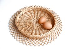 two eggs in a wicker basket on a white surface