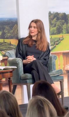 a woman sitting in a chair talking to an audience