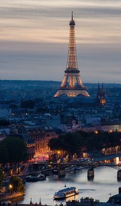 the eiffel tower is lit up at night, with boats in the water below