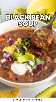 a bowl of black bean soup with tortilla chips and avocado on the side