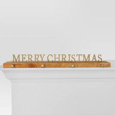 a wooden merry christmas sign sitting on top of a white mantle