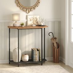 a table with a mirror, vases and books on it next to a door