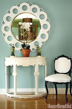 a white table with a potted plant sitting on top of it next to a mirror