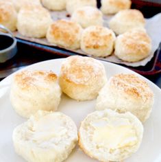 biscuits and butter on a plate next to a baking pan with other baked goods in the background