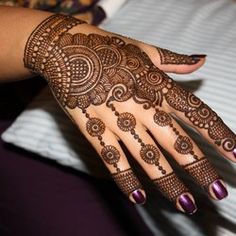 a woman's hand with henna tattoos and purple nail polishes on it