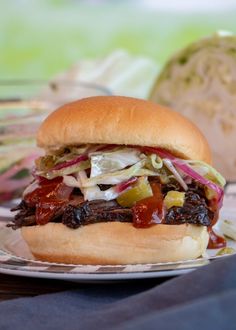 a sandwich on a plate with coleslaw and other toppings next to an onion bun