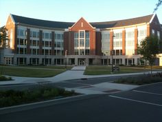 an empty street in front of a large building with many windows and grass on the side