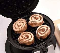 four cinnamon rolls are being cooked in a waffle maker