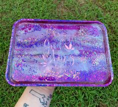 someone is holding up a purple tray with glitter on it