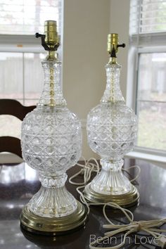 two glass lamps sitting on top of a table