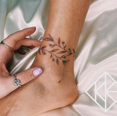 a woman's foot with a flower tattoo on her left ankle and right hand