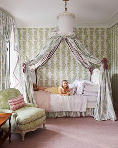 a woman laying on top of a bed in a bedroom next to a green chair