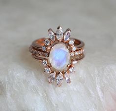 an opal and diamond ring set on top of a marble slab with white stones