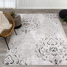 a white rug with black and grey designs on it in a living room area next to a wicker chair