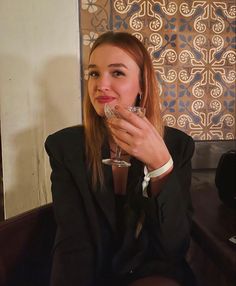 a woman sitting at a table with a drink in her hand