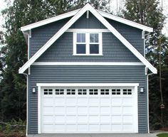 a gray and white house with two garage doors on the front, and three windows on the back