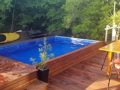 an above ground swimming pool surrounded by wooden decking and trees in the back yard