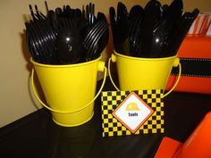 two yellow buckets filled with black plastic forks