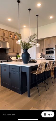 a large kitchen with an island in the middle and chairs at the end, along with lights hanging from the ceiling