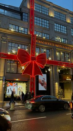 a large red bow hanging from the side of a building on a city street at night