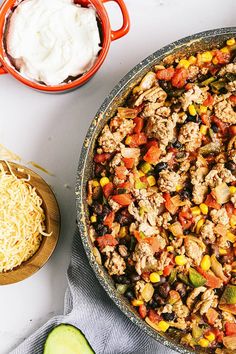 a casserole dish with meat, vegetables and cheese next to a bowl of sour cream