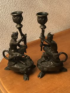 two black candlesticks sitting on top of a wooden table