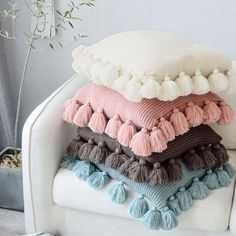 a stack of pillows sitting on top of a white couch next to a potted plant