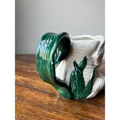 a green and white vase sitting on top of a wooden table