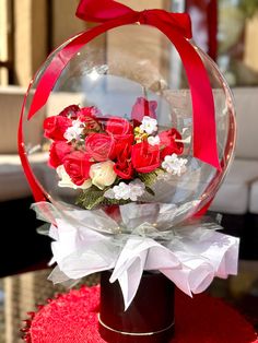 a vase filled with red roses and white flowers on top of a round table cloth