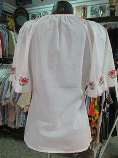 "Beautiful vintage flared etnic blouse. Maybe hungarian or romanian from the 60s. White cotton fabric. Delicious floral hand embroideries on front and sleeves. The colour of the flowers is pink/red. Round keyhole neckline that closes with a stripe (pic.2). Raglan sleeves. Cute flared short sleeves with darts and embroideries (pic.3). Boho/hippy style. Mint conditions. It fits size S-M Measurements: (lay flat and double chest) Shoulders up to 15.7\" chest 36.2\" sleeve length (from neck bottom to Retro Short Sleeve Top With Floral Embroidery, Spring Short Sleeve Blouse With Boho Collar, Vintage Embroidered Short Sleeve Tops, Spring Folk Blouse With Yoke, Traditional Spring Peasant Top With Yoke, Retro Short Sleeve Blouse With Floral Embroidery, Bohemian Embroidered Short Sleeve Peasant Top, Vintage White Peasant Top For Festival, White Vintage Peasant Top For Festival