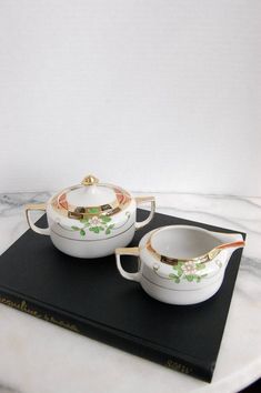 two white dishes sitting on top of a black tray