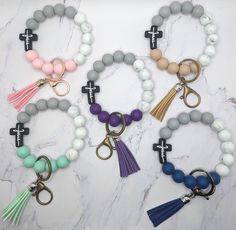 four bracelets with cross charms and tassels on marble counter top next to each other