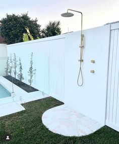 a white fenced in backyard with a small swimming pool and shower head mounted on the wall