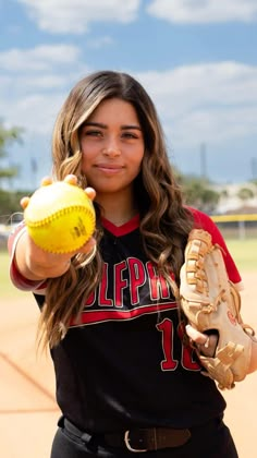 a girl in a baseball uniform holding a ball