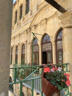 a balcony with potted flowers on the railing and an old building in the background