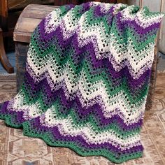 a crocheted blanket sitting on top of a wooden chair next to a table