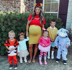 a pregnant woman posing with her children in front of a house wearing costumes for halloween