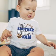 Big Brother will always be his hero. Score a touchdown by getting lil bro a shirt that will cheer on his big brother from the sidelines this season and make picture-perfect memories. Welcome to Sofia and Penelope's! Get ready to fall in love with our Gildan 5000B and Rabbit Skins shirts. It's the perfect combination of softness and style that'll make it your new go-to tee. Our light fabric and tear-away label make it a smart purchase. Make sure to check our size chart for that perfect fit. We are a small business, so we encourage all of our customers to look at the size chart and measure a favorite T-shirt that you have at home to compare. Not all shirt brands fit the same.  We want to make sure that you are delighted with your purchase. If you experience any problems with your order, plea White Tops With Team Name For Fan Events, White Sports Team Tops For Fan Events, Fan Apparel Tops With Character Print For Sports Events, White Character Print Tops For Fan Events, White Tops With Name Print For Fans, Kids Football Shirts, Lil Bro, Shirt Football, Football Kids