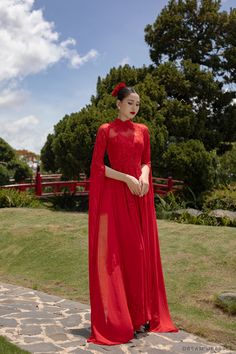 a woman in a red dress standing on a stone walkway