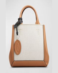 Tod's shopper shoulder bag in leather, linen, and cotton    Rolled top handles with logo tag     Shoulder straps     Open top with side snap closure     Interior, leashed zip pouch bag     Lining: Leather    Approx. 7.8"H x 17.7"W x 4.9"D    Made in Italy Designer Canvas Bag With Top Handle For Errands, Designer Canvas Tote Bag With Top Carry Handle, Designer Canvas Shoulder Bag With Handles, Designer Canvas Tote Bag With Top Handle, Designer Canvas Bag With Double Handle For Daily Use, Designer Canvas Bag With Top Handle For Daily Use, Designer Brown Canvas Bag With Top Handle, Designer Tan Bags With Leather Handles, Top Handle Canvas Shopping Bag