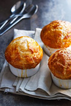 three muffins sitting on top of a napkin next to a fork and spoon