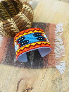 two woven bracelets sitting on top of a wooden table next to a wicker basket