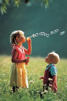 two young children blowing bubbles in a field