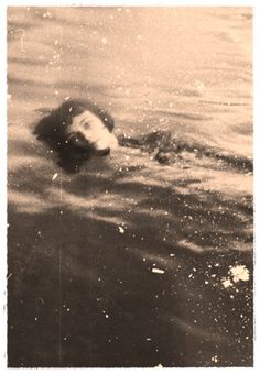 a black and white photo of a dog swimming in the water with it's head submerged